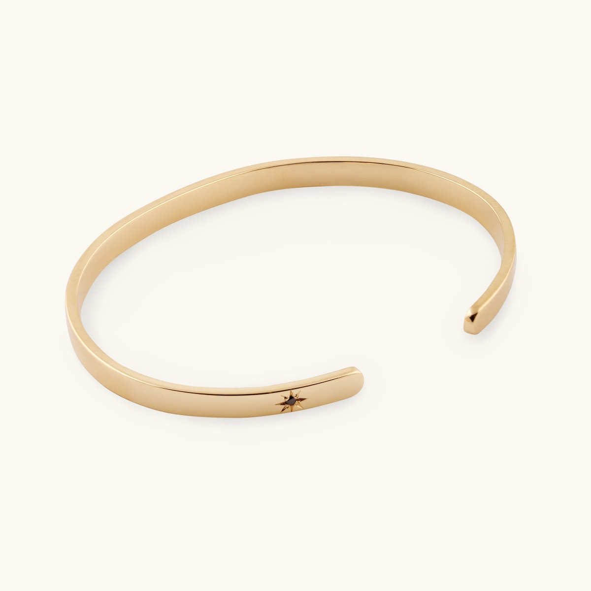 A bangle in 18K gold with a black diamond with a star frame