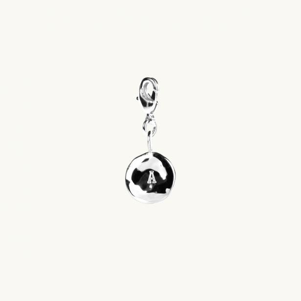 A letter coin in silver with an organic shape. 