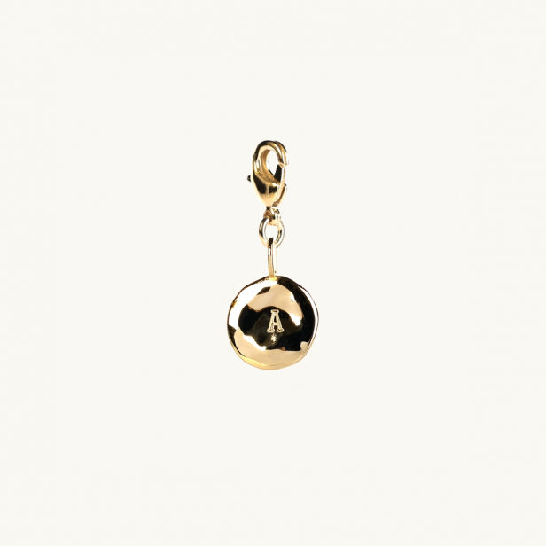 A letter coin in gold with an organic shape. 
