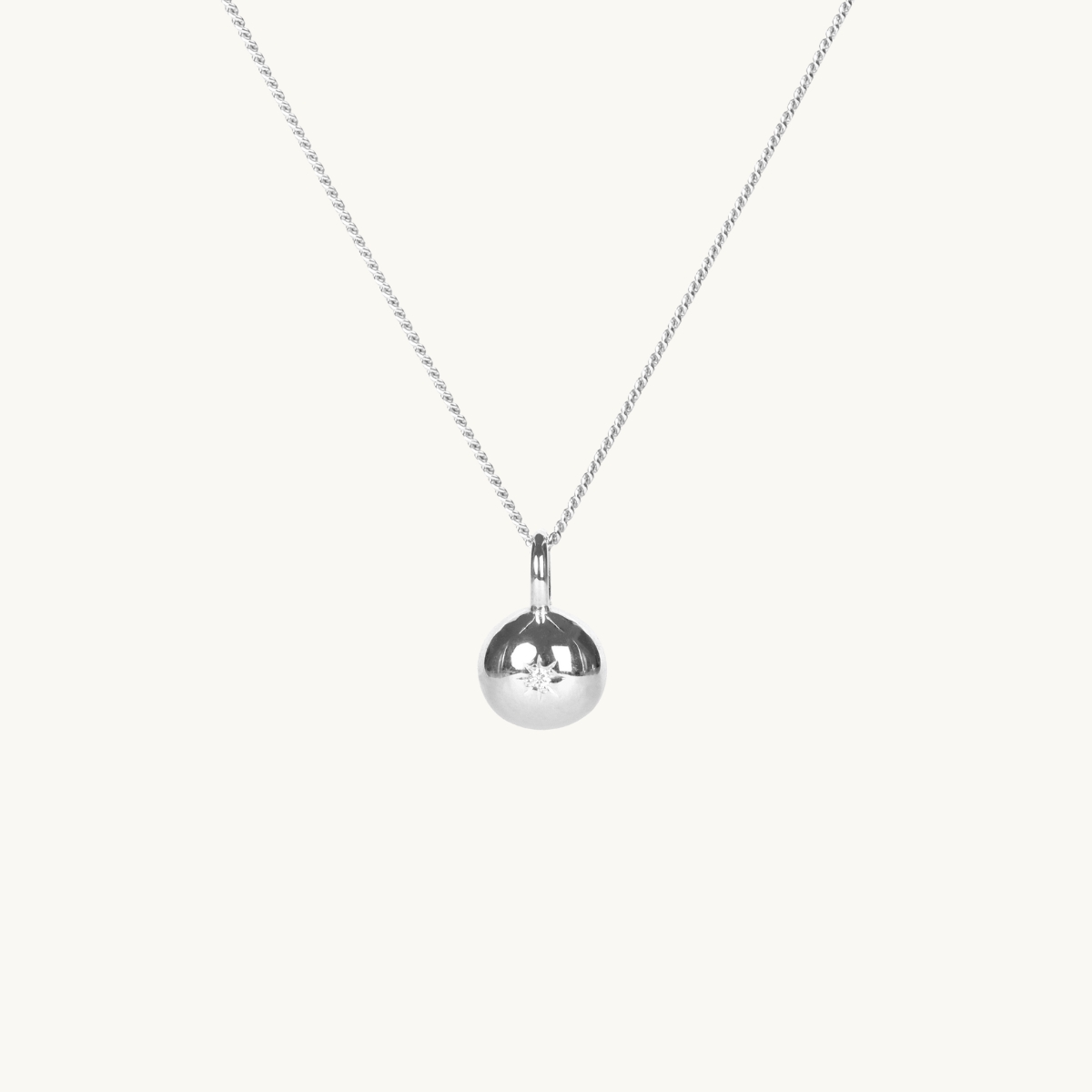 A round pendant in silver with a white diamond on a silver chain