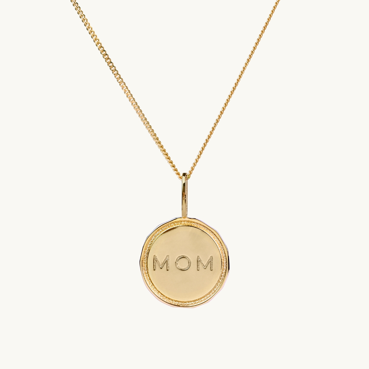 A coin in 18K gold plated brass with the engraving MOM