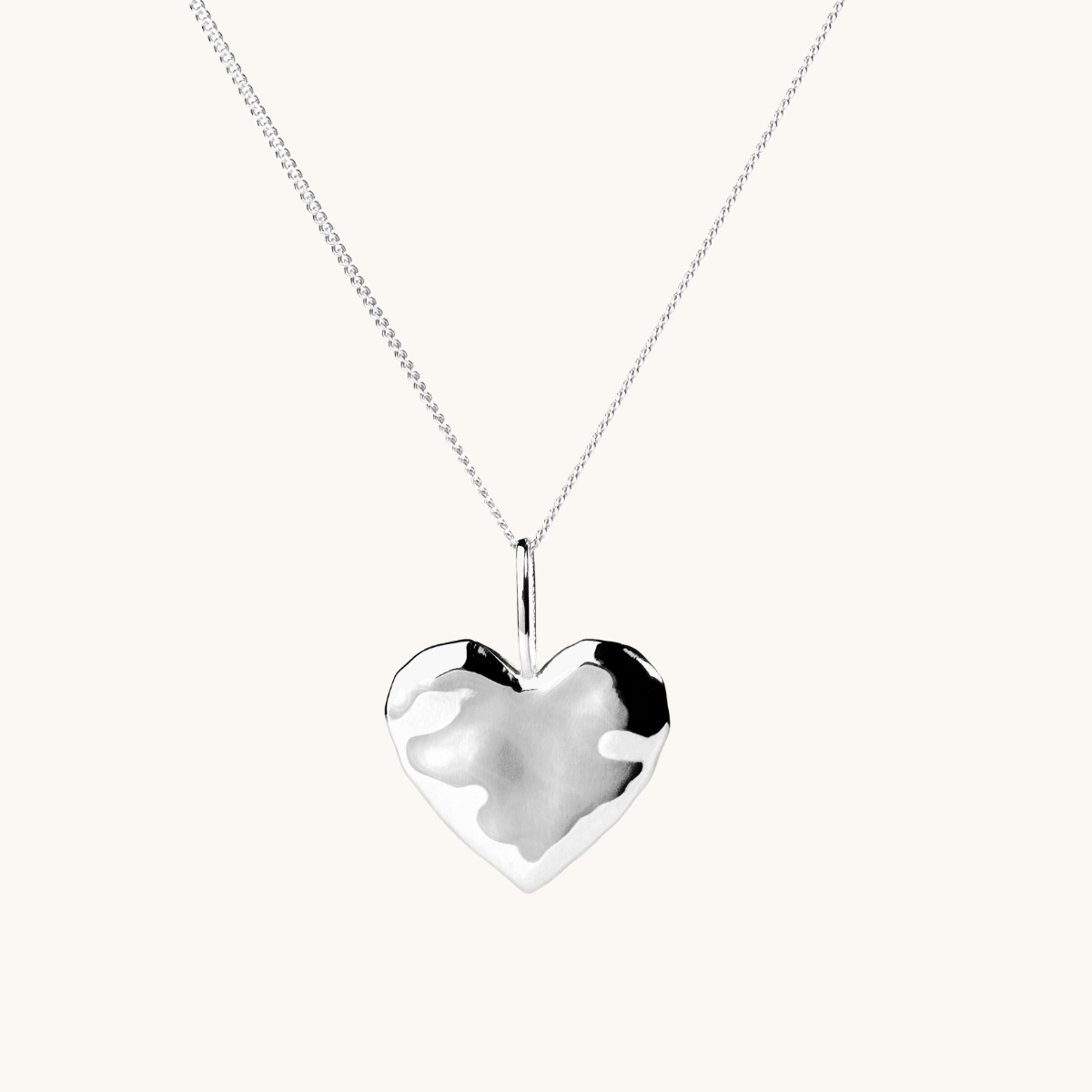 A silver heart necklace with an organic shape
