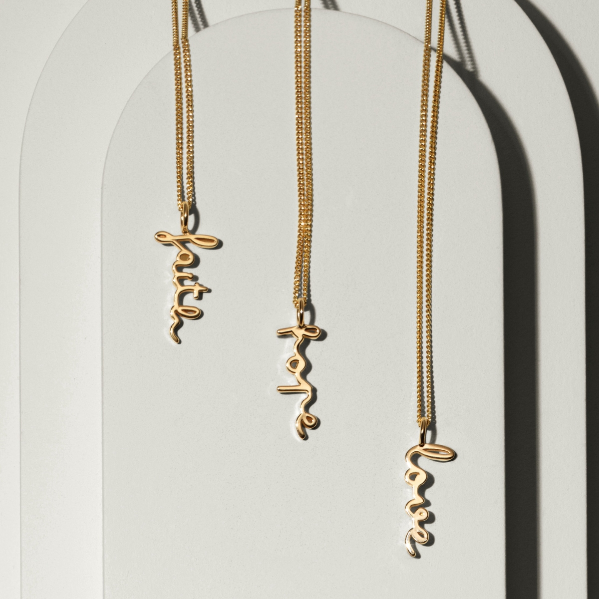 An 18K gold plated brass necklace in lowcase letters with the text faith