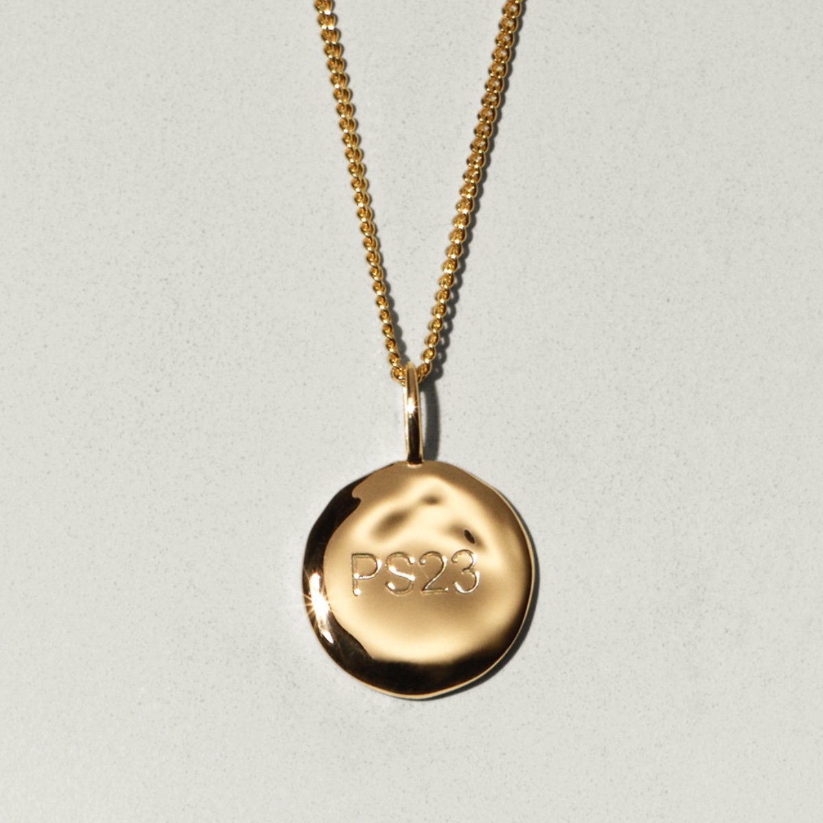 a gold coin with the text ps23