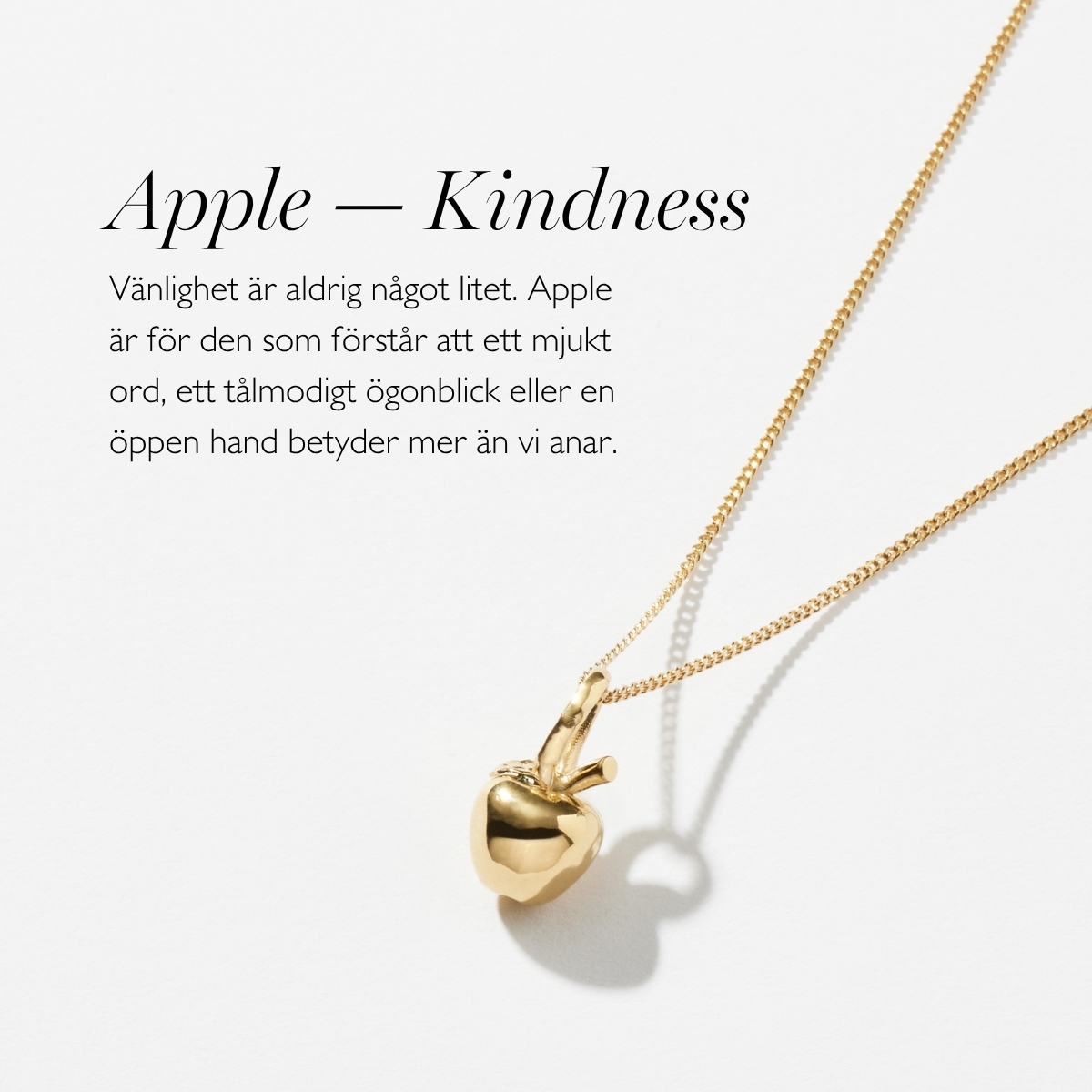 A silver necklace with a pendant in shape of an apple
