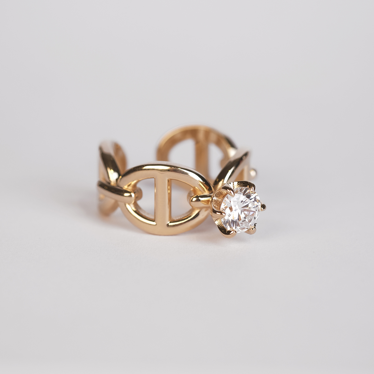A silver ring with anchor pattern and a white diamond