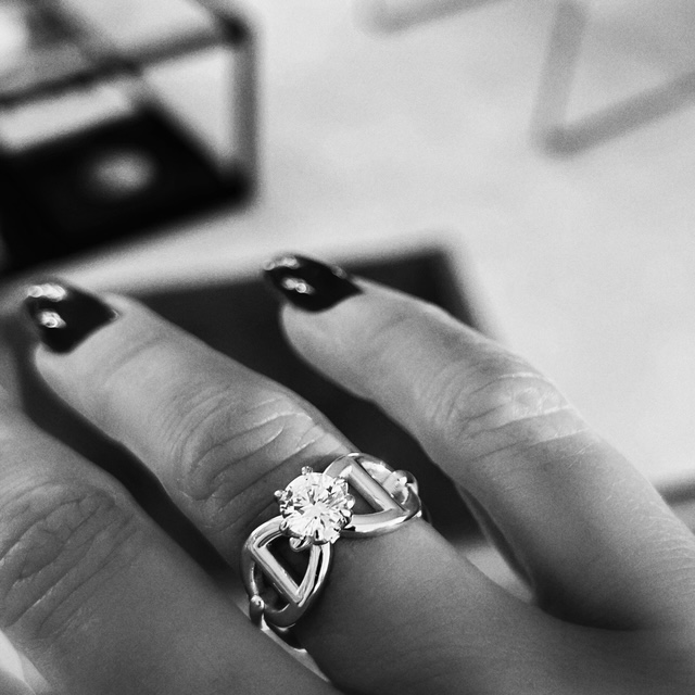 A silver ring with anchor pattern and a white diamond