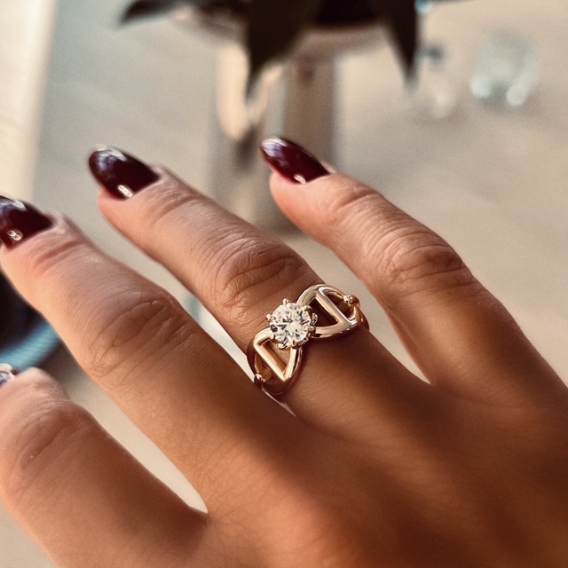 A gold ring with anchor pattern and a white diamond