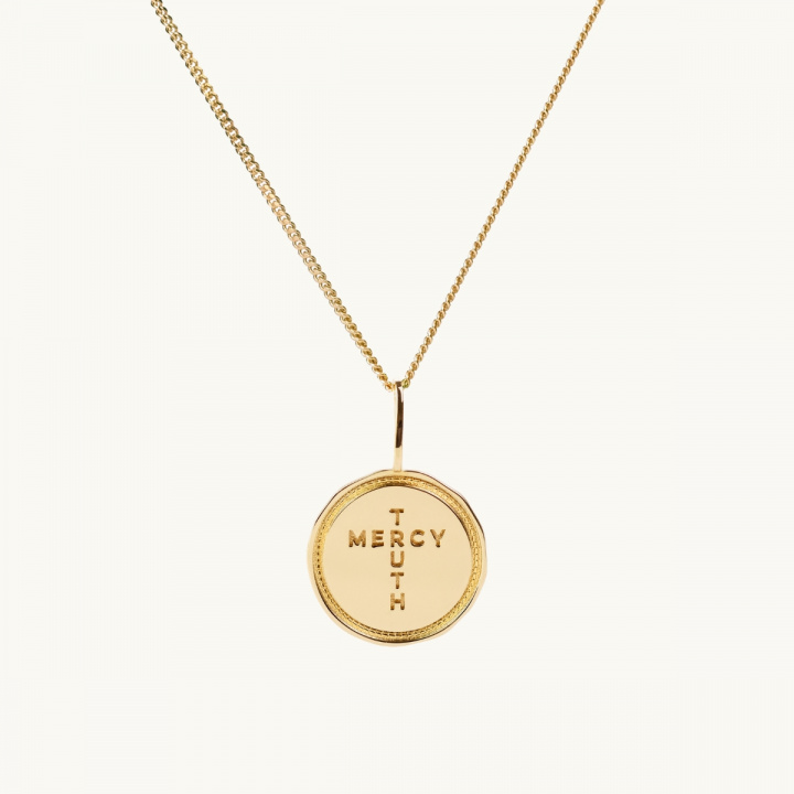 A coin in gold with the inscription Truth Mercy