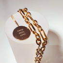 A gold coin with the engrave faith, hope, love together with a chunky chain in gold