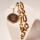 A gold coin with the engrave faith, hope, love together with a chunky chain in gold