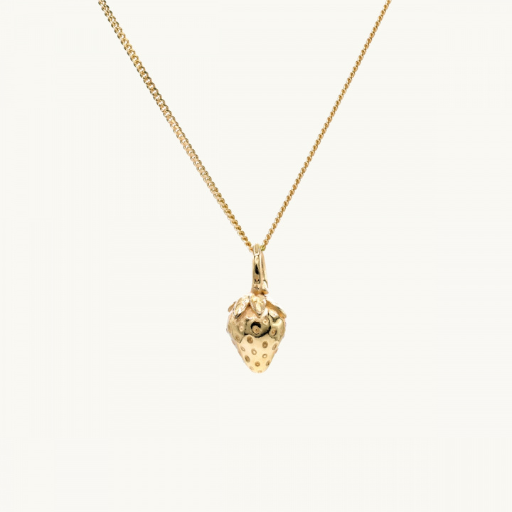 A gold necklace with a pendant in shape of a strawberry