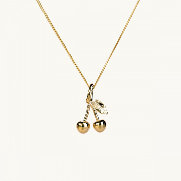 A gold necklace with a pendant in shape of two cherries