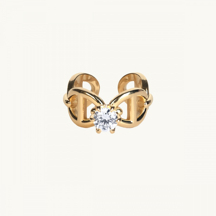 A gold ring with anchor pattern and a white diamond